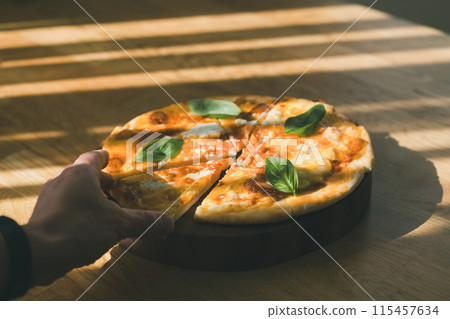 Hand holding freshly baked pizza Hand holding freshly baked pizza 115457634