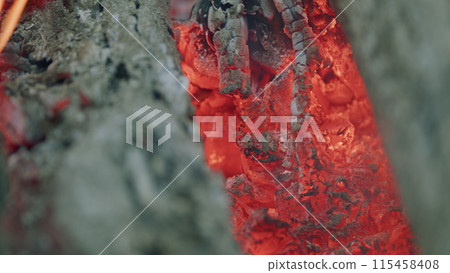 Burning firewood in campfire site. Smoldering and iridescent hot coals. Slow motion. Burning firewood in campfire site. Smoldering and iridescent hot coals. Slow motion. 115458408