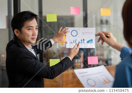 Business Team Discuss Analysis with Charts and Graphs in Modern Office Setting 115458475