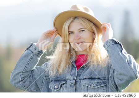 Woman adjusting hat outdoors 115458660