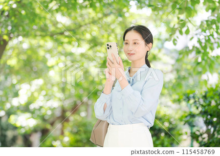 A woman looking at her smartphone among the fresh greenery 115458769