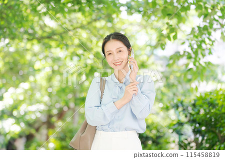 A woman in her 20s making a phone call in the park A woman in her 20s making a phone call in the park 115458819