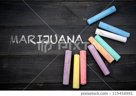 Marijuana. Text and pieces of chalk on a dark wood texture background Marijuana. Text and pieces of chalk on a dark wood texture background 115458991