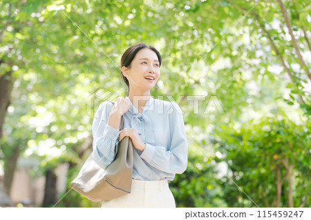 Business woman walking through fresh greenery Business woman walking through fresh greenery 115459247
