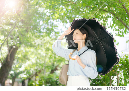 A woman walking through the fresh greenery with a parasol 115459782