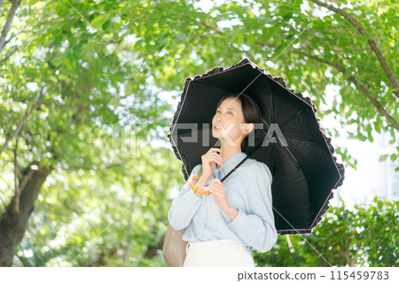 一個女人帶著陽傘走過新鮮的綠色植物 115459783