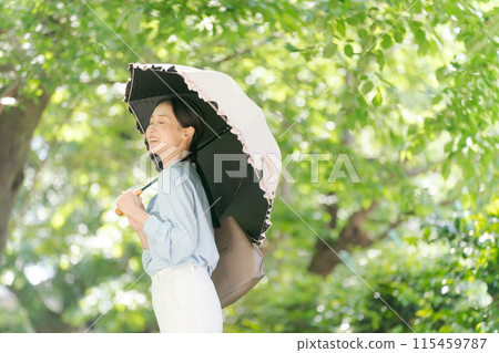 A woman walking through the fresh greenery with a parasol 115459787