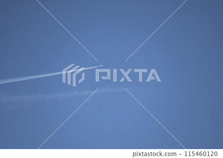 A white airplane and a contrail on a blue sky A white airplane and a contrail on a blue sky 115460120
