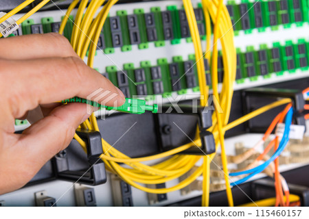 closeup of hand of administrator connecting network cable into switch 115460157