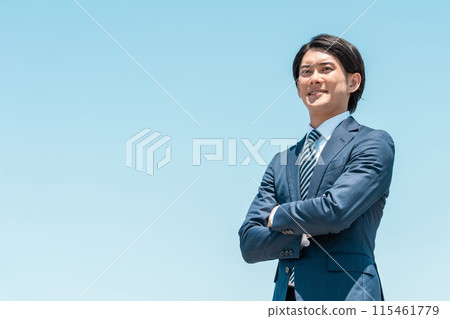 微笑的年輕亞洲商人雙手交叉在藍天上 115461779