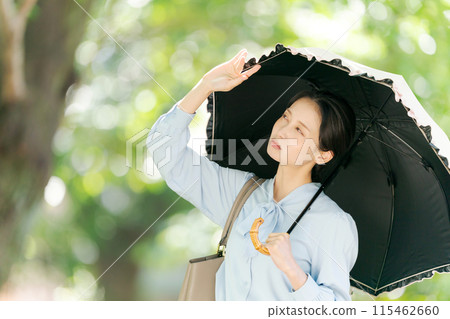 A woman with a troubled expression in the strong sunlight 115462660