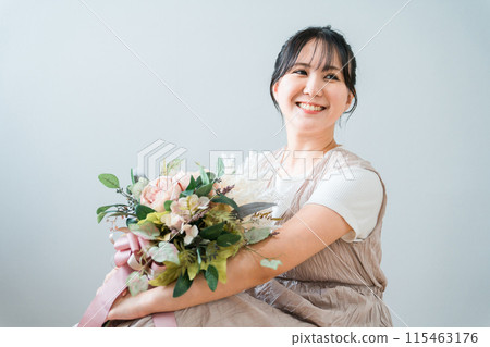 A stylish woman holding a swag of dried flowers A stylish woman holding a swag of dried flowers 115463176