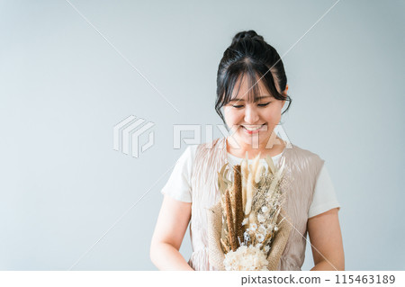 A stylish woman holding a swag of dried flowers 115463189