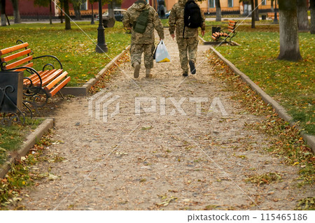 Ukrainian soldiers in a park during autumn, wearing military uniforms. Autumn scene with Ukrainian army personnel in uniform patrolling a park. War in Ukraine 115465186