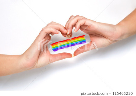 Hand with rainbow heart, LGBTQ rights, pride month. White background. Woman hands making a heart gesture. Colorful pride flag, symbol of LGBTQ love, celebration 115465230