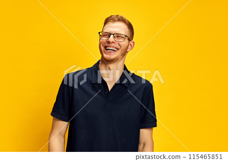 Portrait of young redhead man in glasses posing, cheerfully laughing against bright yellow background. Happiness, success and joy 115465851