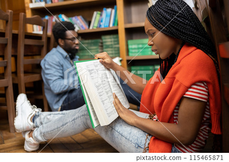 Young people studying in the library together and looking involved Young people studying in the library together and looking involved 115465871