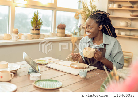 Smiling female sculptor holding a new mug in hands 115466053