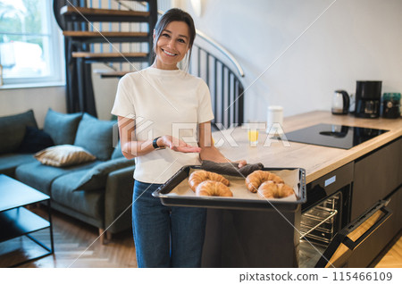 Dark-haired woman with a tray of fresh homemade croissants looking happy Dark-haired woman with a tray of fresh homemade croissants looking happy 115466109