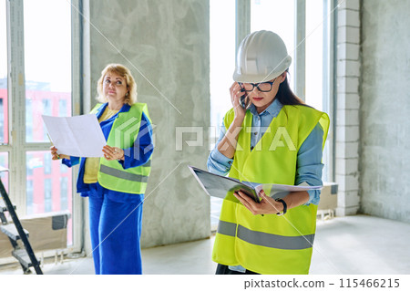 Industrial profession worker female in protective vest helmet working on construction. Industrial profession worker female in protective vest helmet working on construction. 115466215