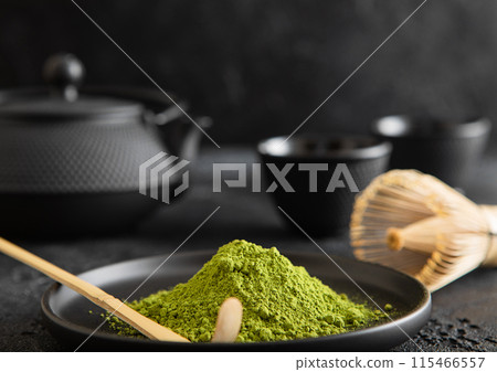 Plate with green matcha tea with bamboo spoon and whisk and japanese iron cast kettle on black. 115466557