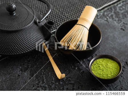 Green matcha tea with bamboo spoon and whis and japanese iron cast kettle on black. Green matcha tea with bamboo spoon and whis and japanese iron cast kettle on black. 115466559
