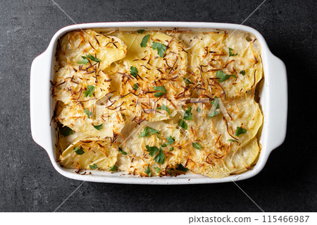 Potato gratin baked with cream and cheese on black slate background 115466987