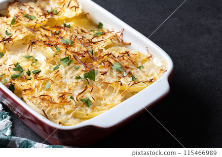 Potato gratin baked with cream and cheese on black slate background Potato gratin baked with cream and cheese on black slate background 115466989