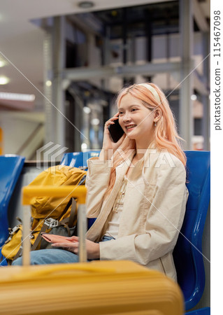Young Woman Traveling Through Airport, Smiling and Talking on Phone, Sitting with Luggage, Ready for Adventure, Modern Travel, Casual Style, Excited for Journey, Airport Terminal Background Young Woman Traveling Through Airport, Smiling and Talking on Phone, Sitting with Luggage, Ready for Adventure, Modern Travel, Casual Style, Excited for Journey, Airport Terminal Background 115467098