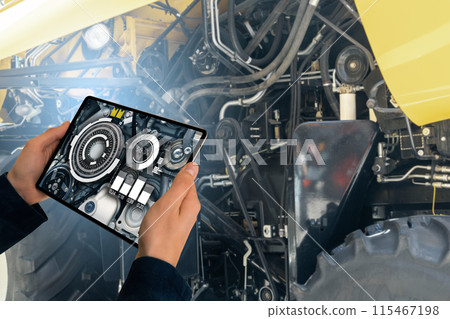 Serviceman with digital tablet next to combine harvester with open hood. Serviceman with digital tablet next to combine harvester with open hood. 115467198