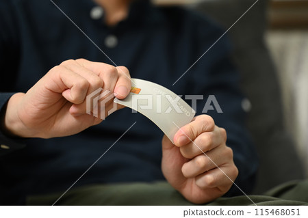 Close up upset young man breaking his credit card. Financial problems and debt free concept 115468051