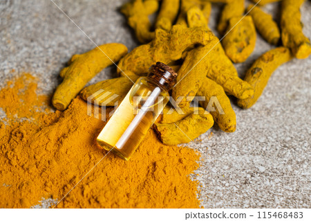 Natural Turmeric Oil in a Glass Bottle with Ground Turmeric Powder and Dry Turmeric Root. 115468483