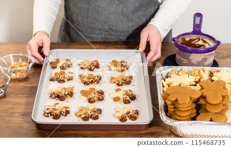 Gingerbread men cookies, chocolate-dipped feet, generously sprinkled with golden toasted coconut shavings, artfully arranged on parchment paper. 115468735