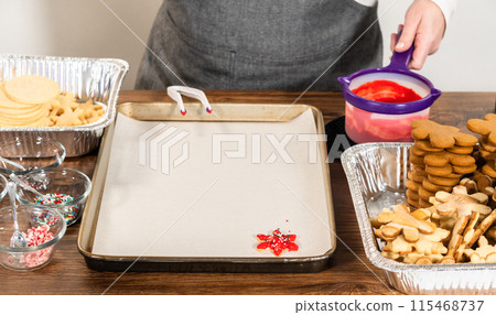 Vivid red star-shaped cookies, generously iced and speckled with green and white holiday sprinkles, freshly prepared and laid out to dry. 115468737