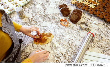 Using various festive cookie cutters, we're cutting out charming gingerbread cookies from the rolled dough on the sleek marble counter, bringing holiday cheer to the modern kitchen. 115468739