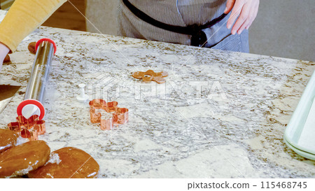 Using an adjustable rolling pin to roll out gingerbread cookie dough on the elegant marble counter in a modern kitchen, getting ready for festive holiday baking. 115468745