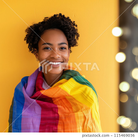 Smiling woman wrapped in rainbow flag, standing against solid yellow background. Concept LGBTQ pride 115469036