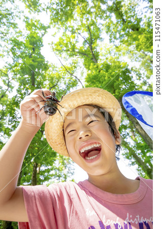 Boy holding a rhinoceros beetle in a wooded area Boy holding a rhinoceros beetle in a wooded area 115471063