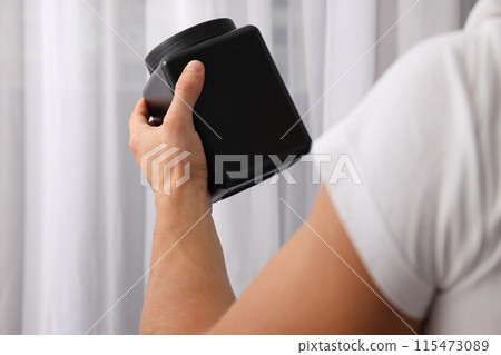 Black plastic jar in male hand on light background Black plastic jar in male hand on light background 115473089