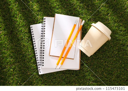 A paper notebook with a pencil on the grass. A paper notebook with a pencil on the grass. 115473101