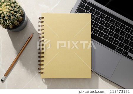 Notebooks lie near a laptop on a light background Notebooks lie near a laptop on a light background 115473121