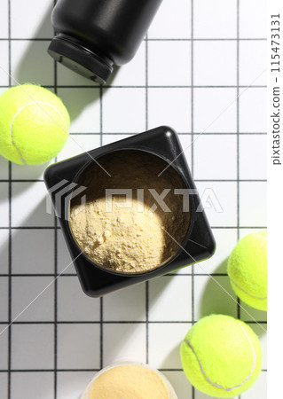 Black plastic jars and tennis balls on light background, top view Black plastic jars and tennis balls on light background, top view 115473131