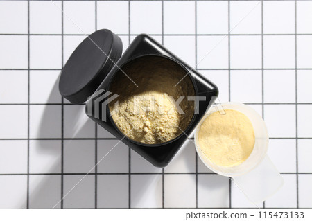 Black plastic jar and measuring cup with powder on light background, top view Black plastic jar and measuring cup with powder on light background, top view 115473133
