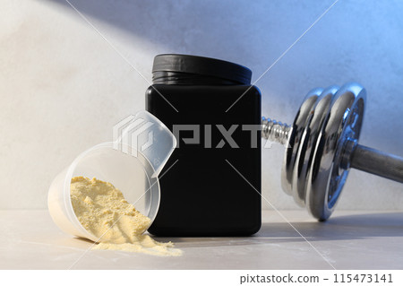 Black plastic jar, measuring cup with powder and dumbbell on light background 115473141