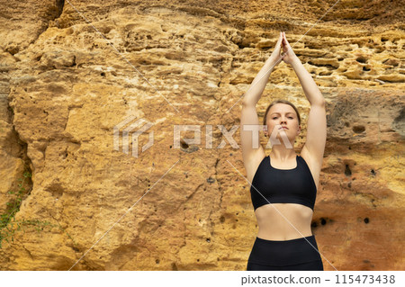 Young slim woman in sportswear doing yoga on rock, space for text Young slim woman in sportswear doing yoga on rock, space for text 115473438