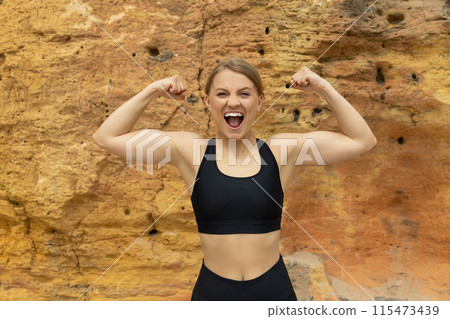 Young strong woman in sportswear screams on rock 115473439
