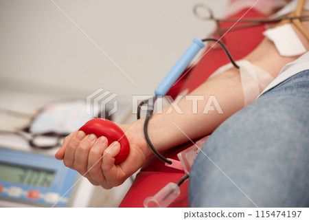 Hand of unrecognizable blood donor squeezing red heart-shaped rubber toy during transfusion process Hand of unrecognizable blood donor squeezing red heart-shaped rubber toy during transfusion process 115474197