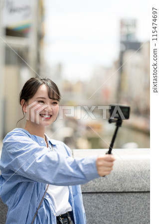 Young and pretty woman taking a selfie in the city's downtown | Osaka Tourism Image | Dotonbori, Osaka Prefecture | Ebisubashi Bridge 115474697