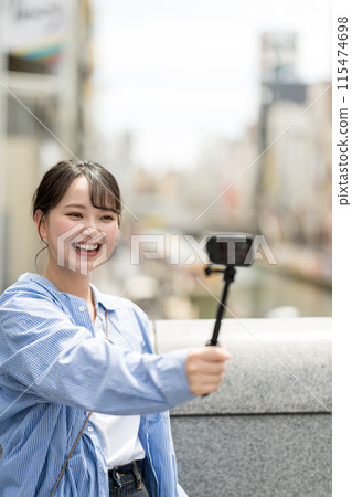 Young and pretty woman taking a selfie in the city's downtown | Osaka Tourism Image | Dotonbori, Osaka Prefecture | Ebisubashi Bridge 115474698