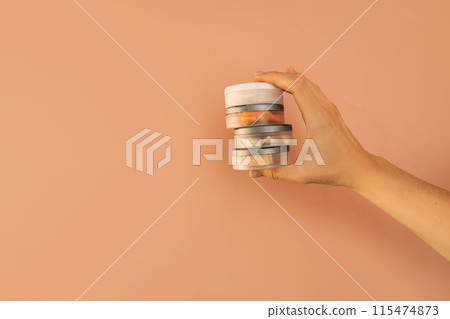 Hand holding plastic jars filled with snus against brown background Hand holding plastic jars filled with snus against brown background 115474873